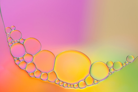 colorful oil bubbles on a water surface abstract background with purple, pink, yellow, green and...