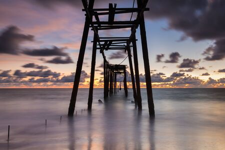 sea waves lash line impact on the sand beach with old wood bridge at sunset, pilai beach, phang nga , thailandの写真素材