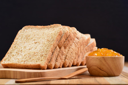 slices bread with orange jam on wooden tableの写真素材