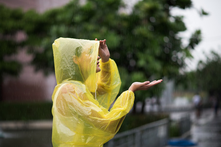Portrait of the women wearing yellow raincoat while raining in rainy seasonの写真素材