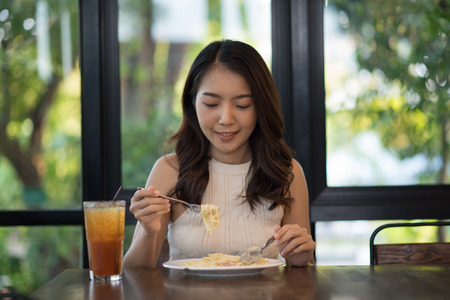 Portrait of Young Asian woman eating spaghetti carbonaraの写真素材