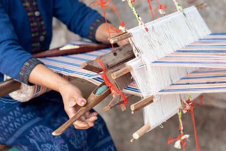 Close-up of women's hands weaving with traditional Thai weaving machineの写真素材