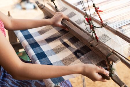Close-up of women's hands weaving with traditional Thai weaving machineの写真素材