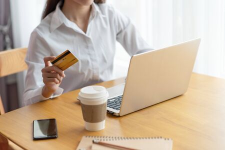 Close-up of woman holding credit card and using laptop for online shopping