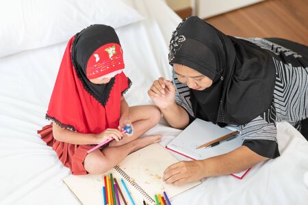 Young muslim girl hand using pencil sharpener for sharpening colored pencils with grandma, education conceptの写真素材