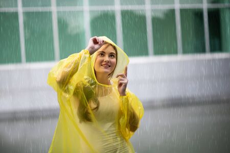 Portrait of the women wearing yellow raincoat while raining in rainy seasonの写真素材