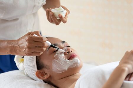 Young Asian woman in mask on face in spa beauty salon, enjoying and relaxing time, skin care and healthcare conceptの写真素材