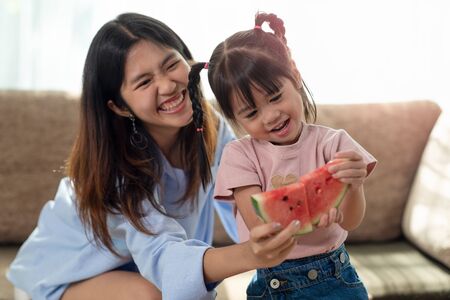 Happy Asian child enjoy eating a ripe juicy watermelon with her older sister, love and happiness family conceptの写真素材