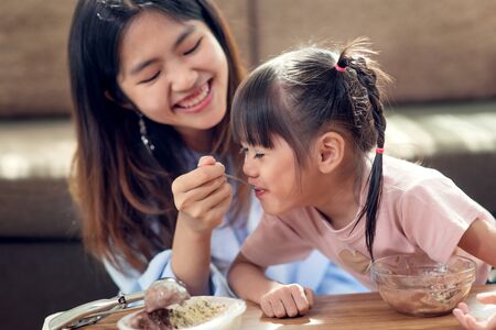 Happy Asian child enjoy eating ice cream with her older sister, love and happiness family conceptの写真素材