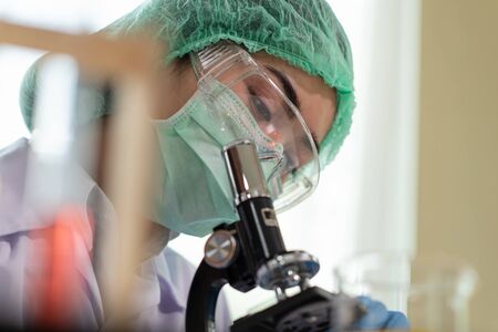 Young Asian women scientist looking through a microscope in a laboratory, Science and chemistry...