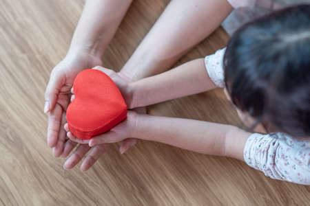 Mother and child daughter hands holding red heart gift boxes, Happy Asian family conceptの写真素材