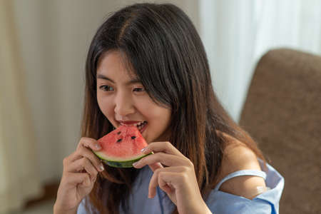 Portrait happy young Asian woman is enjoy eating slice of watermelonの写真素材