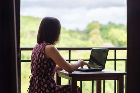 Beautiful young Asian businesswoman working with laptop at her house, work from home, business conceptの写真素材