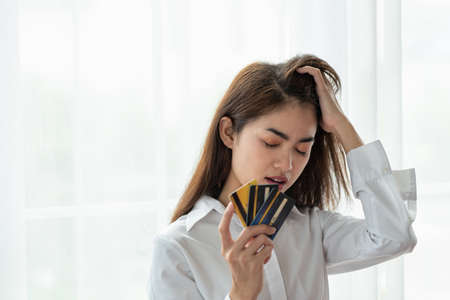 Stressed Young Asian business woman holding credit card with feeling unhappy, Financial problem conceptの写真素材