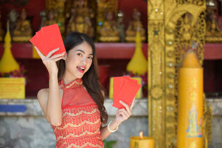 Young happy Asian woman wear cheongsam holding red envelopes in Chinese New Yearの写真素材