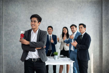 Happy Businessman holding up a winning trophy Many hands applauding behind, Business conceptの写真素材