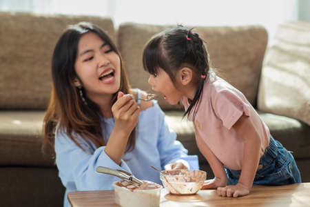 Happy Asian child enjoy eating ice cream with her older sister, love and happiness family conceptの写真素材