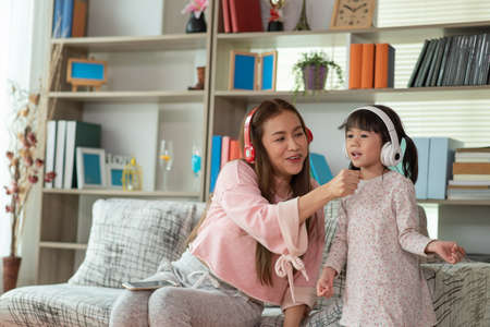 Happy Asian child having fun and dancing with her mother in a room, active leisure and lifestyle conceptの写真素材