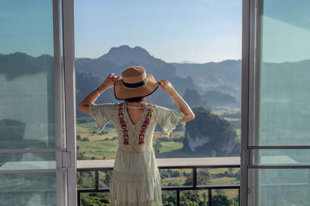 Young Asian woman traveler relaxing and watching a beautiful mountain view with nature in the morningの写真素材