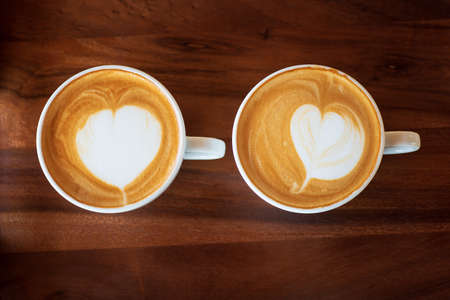 close-up of a cup of hot latte art coffee on wooden tableの写真素材