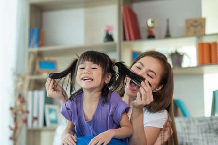 Mother having fun and playing with her daughter at home, Happy Asian little child, family conceptの写真素材