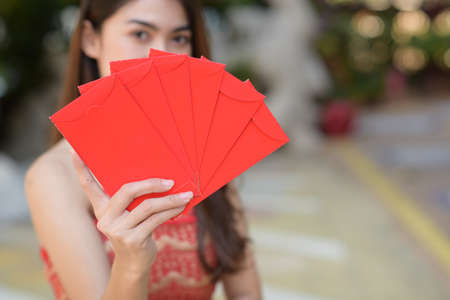 Close up of Asian woman wear cheongsam holding red envelopes in Chinese New Yearの写真素材