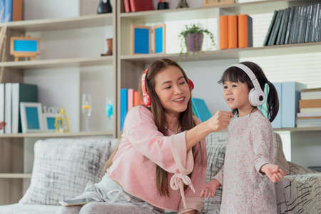Happy Asian child having fun and dancing with her mother in a room, active leisure and lifestyle conceptの写真素材