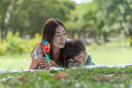 Happy Asian family having fun mother and her son playing windmill in the garden togetherの写真素材