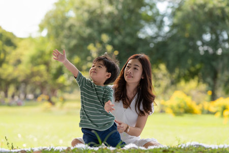 Happy Asian family having fun mother and her son playing in the park together