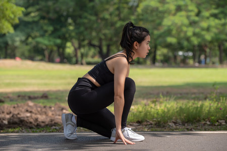 Sportive woman working out outdoors, Sporty young Asian runner woman doing exercises and ready to start running, sport and healthy lifestyle conceptの写真素材