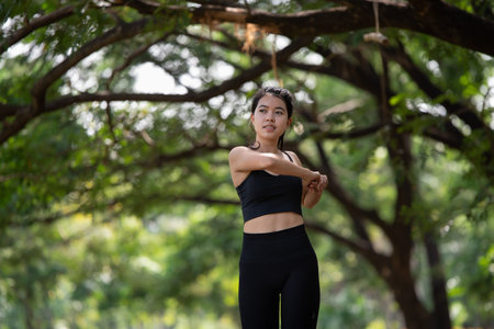 Sporty young Asian woman doing stretching warm up before exercise outdoors in park, sport and healthy lifestyle conceptの写真素材