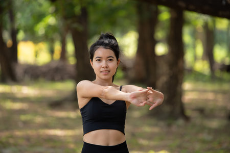 Sporty young Asian woman doing stretching warm up before exercise outdoors in park, sport and healthy lifestyle conceptの写真素材