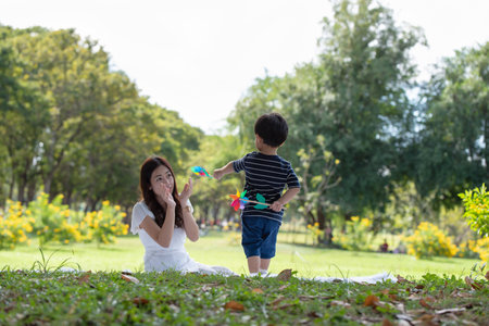 Happy Asian family having fun mother and her son playing windmill in the garden togetherの写真素材