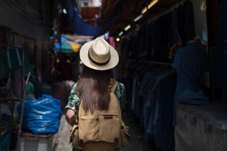 Young Asian female tourist traveling and shopping stall at outdoor local street market in Bangkok...