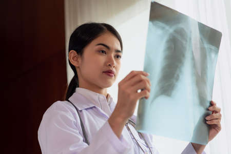 Female radiology doctor examining at x ray film of patient at hospital room, lung radiography, Healthcare and Medical conceptの写真素材