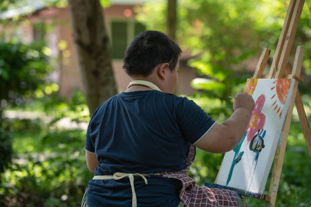 Cute happy little Asian boy painting with watercolor on canvas standing, child creative activities, education in artの写真素材