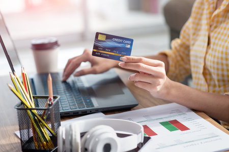 Close-up of woman holding credit card and using laptop for online shoppingの写真素材