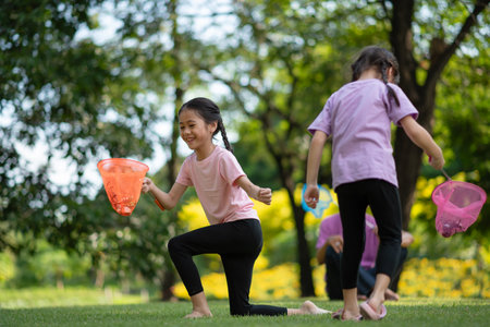 Happy Asian family children having fun and catches a net of insects with her grandfather in the park, summer vacation conceptの写真素材