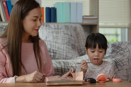 Happy child, Little Asian girl doing makeup with her mother, loving family conceptの写真素材
