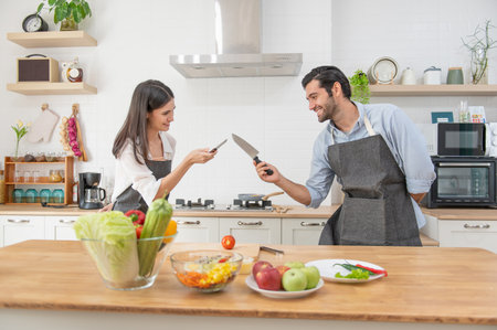 Happy young couple cooking together in the kitchen counter at home