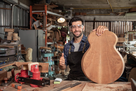 Portrait of guitar luthier small business owner in workroom, arts and craft conceptの写真素材