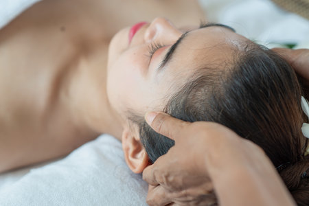Young Asian woman receiving head massage, enjoying and relaxing in spa salonの写真素材