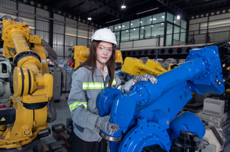 Engineer with helmet safety standing by robotic arm and operating machine in industry factory, technician worker check for repair maintenance electronic operationの写真素材