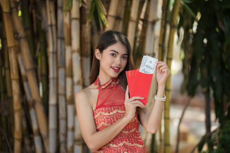 Young happy Asian woman wear cheongsam holding red envelopes in Chinese New Yearの写真素材