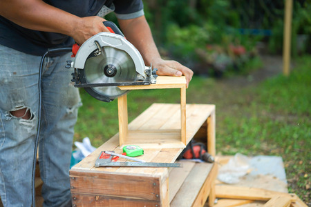 Asian carpenter are sawing the wood in the backyard garden at home.の写真素材