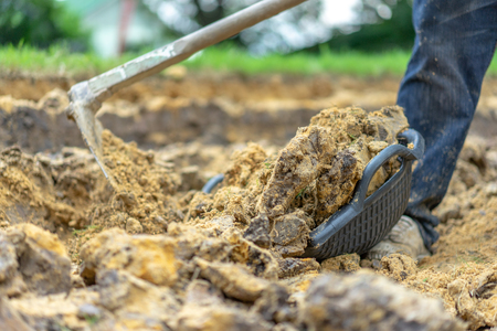 gardener digs the soil with his equipment for gardening and prepare land for plantation.の写真素材