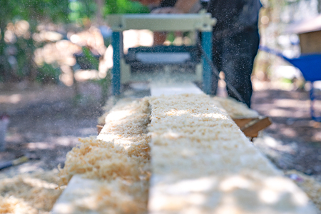 worker scrubs the big long wood plate with polishing machine in the garden.の写真素材