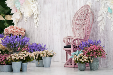 Luxury vintage bamboo chair front of white wood backdrop and many flower around.の写真素材