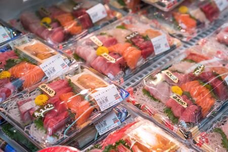 Osaka, Japan - 3 Mar 2018; Japanese local fresh foods; sea food, fish, sashimi, fruits, stawberrry, puffer, salmon, dried food, crab, etc, tourists walking and eating at Kuromon Ichiba Market (fish market)のeditorial素材