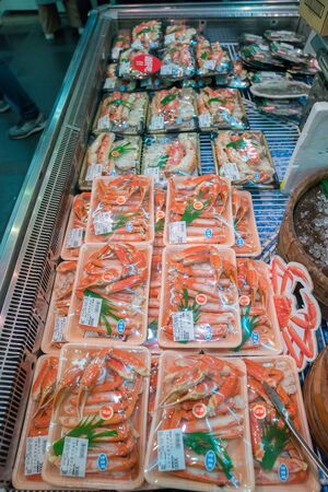 Osaka, Japan - 3 Mar 2018; Japanese local fresh foods; sea food, fish, sashimi, fruits, stawberrry, puffer, salmon, dried food, crab, etc, tourists walking and eating at Kuromon Ichiba Market (fish market)のeditorial素材